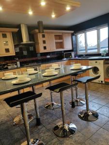 a kitchen with a counter with stools in it at Super 7Bed House - Hot Tub - Large Gathering Meets in Headingley