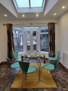 comedor con mesa de cristal y sillas verdes en Super 7Bed House - Hot Tub - Large Gathering Meets, en Headingley
