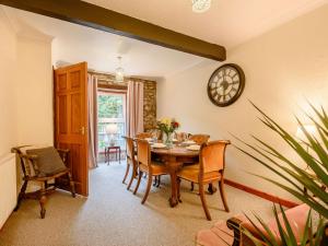 a dining room with a table and chairs and a clock at 3 Bed in Ferryside 88784 in Ferryside