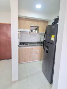 a kitchen with a black refrigerator and wooden cabinets at Acogedor Piso 5 in Cartagena de Indias