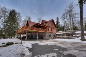 a large wooden house with a deck in the snow at Waterfront Old Forge Cabin with Deck and Indoor Pool in Old Forge