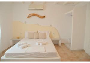 1 dormitorio con cama blanca y almohadas blancas en Anemelia Hotel Adamas, en Adamas