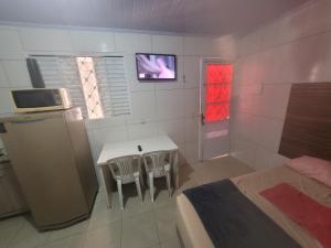 a bedroom with a table and two chairs and a television at 01 arniqueira df simples in Brasilia