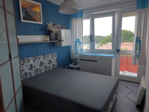 a small bedroom with a bed and a blue wall at Morski Apartament 2 in Ustka