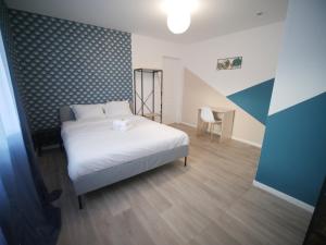 una camera con un letto bianco e una sedia di NG SuiteHome l Lille l Roubaix Gare l Cassel - Netflix - Wifi a Roubaix