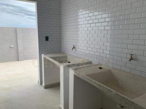La salle de bains est pourvue d'un grand lavabo et de murs blancs. dans l'établissement Yovanna Elegante Apartamento 1 dormitorio, à Santa Cruz de la Sierra