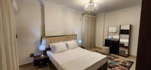- une chambre avec un lit blanc et un lustre dans l'établissement Luxury Apartment near cairo airport, au Caire