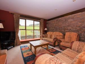 a living room with couches and a stone wall at 4 Bed in Whaley Bridge PK535 in Whaley Bridge