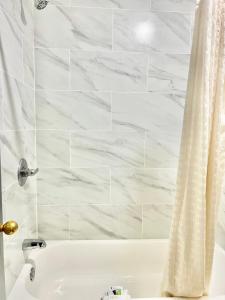 El baño incluye bañera blanca con cortina de ducha. en Palace Motel DEQUEEN, en De Queen