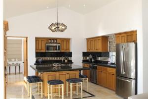 a kitchen with wooden cabinets and a stainless steel refrigerator at Oceanfront Penthouse, 2 Masters, 2 Baths, kitchen! in Cabo San Lucas