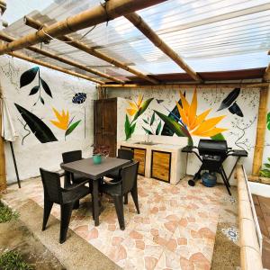een patio met een tafel en stoelen en een muur met bloemen bij Casa Passaro 2 in Calarcá