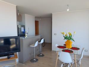 Una sala de estar con una mesa y sillas y un televisor. en departamento nuevo amoblado sin uso, en Viña del Mar