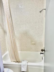 baño con bañera blanca y cortina de ducha en Palace Motel DEQUEEN, en De Queen