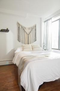 a white bedroom with a large bed with a window at American Dream Guest House in New York