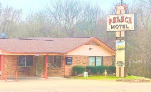 a hotel sign on a pole in front of a building at Palace Motel DEQUEEN in De Queen