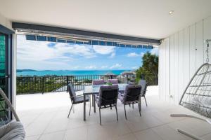 a table and chairs on a patio with a view of the ocean at Holiday on The Horizon Airlie Beach Holiday Home in Airlie Beach