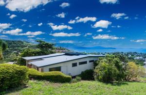 a white house with a roof on a hill at Holiday on The Horizon Airlie Beach Holiday Home in Airlie Beach
