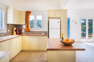 una cocina con armarios amarillos y un bol de fruta en una barra en Villa Zenia Syros en Vari