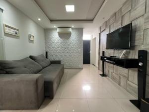 ein Wohnzimmer mit einem Sofa und einem Flachbild-TV in der Unterkunft Apartamento Térreo Charmoso in Cabo Frio