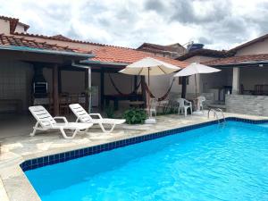 皮雷諾波利斯的住宿－Casa 2M no Centro de Piri，房屋旁的游泳池配有椅子和遮阳伞