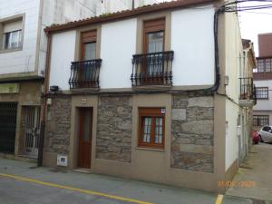 an old stone building with balconies on a street at CASA MARIÑEIRA in Pobra do Caramiñal