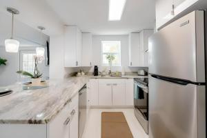 a white kitchen with white cabinets and a refrigerator at Heated pool just 1.7 mi to beach The Ocean Pearl in Sarasota