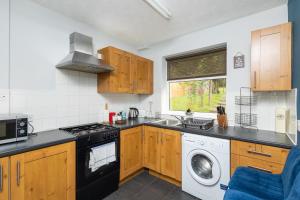 a kitchen with wooden cabinets and a washing machine at Entire home in Seacroft, Leeds, UK in Roundhay