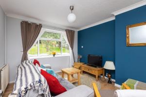 a blue living room with a couch and a tv at Entire home in Seacroft, Leeds, UK in Roundhay