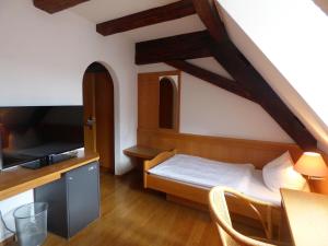 a room with a bed and a table with a tv at Hotel Krone in Pfullendorf
