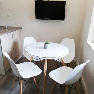 mesa blanca con 4 sillas blancas y TV en Departamentos Santa Bárbara, en Osorno