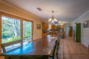 a dining room with a long table and a kitchen at Guadalupe River Getaway - 140 Feet of Beautiful Waterfront! in New Braunfels