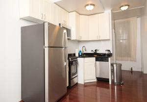 La cuisine est équipée de placards blancs et d'un réfrigérateur en acier inoxydable. dans l'établissement Private Loft in Hells Kitchen near Times Square, à New York