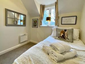 um quarto com uma cama com um cão na almofada em Cosy Cotswold Lodge by Your Home Here, ideal for families with log-burner, spa, private parking and heated swimming pools em Ashton Keynes