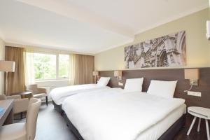 Cette chambre d'hôtel comprend deux lits, une table et des chaises. dans l'établissement Fletcher Hotel-Restaurant ‘s-Hertogenbosch, à Bois-le-Duc