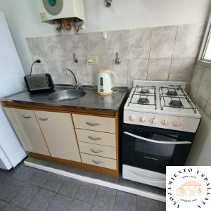 a small kitchen with a stove and a sink at Departamento con Patio y Cochera in San Luis