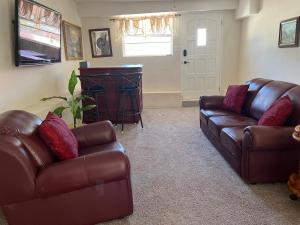 a living room with two leather couches and a television at ABBE Garden Hideaway in Saint Philip