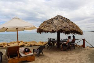 um grupo de pessoas sentadas sob um guarda-sol na praia em Hotel Costa Mar Coveñas em Coveñas