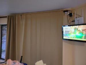 een flatscreen-tv aan een muur met een gordijn bij Departamento céntrico in Tres Arroyos