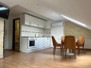 a kitchen with white cabinets and a table and chairs at Art Studio in Niš