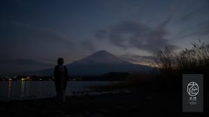富士河口湖町にある富士河口湖温泉　富士山の見える温泉旅館　大池ホテルの夜の山の前に立つ男