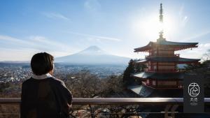 un hombre de pie en un banco mirando a una montaña en Oike Hotel, en Fujikawaguchiko