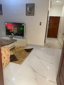 sala de estar con TV y suelo de mármol en Appartement meublé deux pièces, en Agblangandan