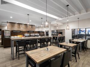 um restaurante com mesas e cadeiras de madeira e janelas em Holiday Inn Calgary Airport, an IHG Hotel em Calgary