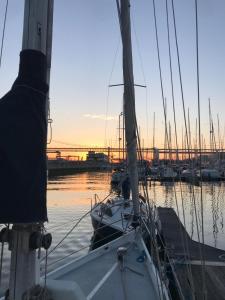 Cozy Lisbon Marina Sleepaboard - Sail Away في لشبونة: قارب شراعي مرسى في الميناء عند غروب الشمس