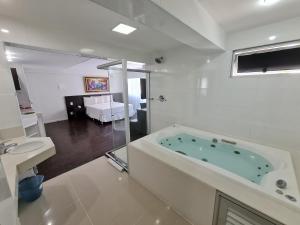 uma casa de banho branca com uma banheira e um lavatório em Hotel San Diego Pampulha - Flats Particular em Belo Horizonte