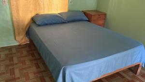 a bedroom with a bed with blue sheets and a dresser at Tico Room in Quepos