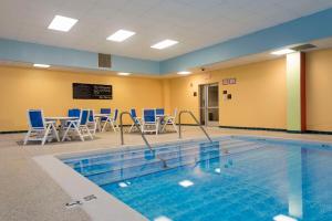 a swimming pool with chairs and a table in a room at Hampton Inn Grand Rapids-South in Wyoming