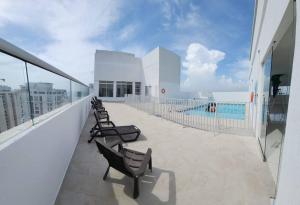 een balkon met stoelen en een zwembad in een gebouw bij Cozy/Exclusive 17th floor apartment with sea view in Cartagena