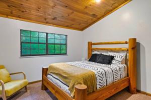 1 dormitorio con cama de madera y silla en NEW HOT TUB! Secluded 3 Bed Cabin in Pigeon Forge en Pigeon Forge