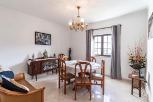 a dining room with a table and chairs and a chandelier at La Familia House in São Teotónio